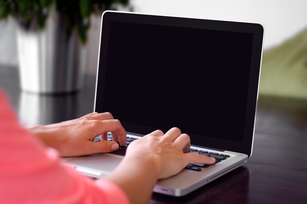 Hands typing on a laptop keyboard, illustrating AI CV screening of online job applications