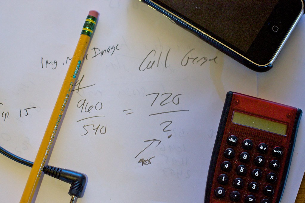 Calculator and figures on paper, illustrating how to compare AI model prices per million tokens
