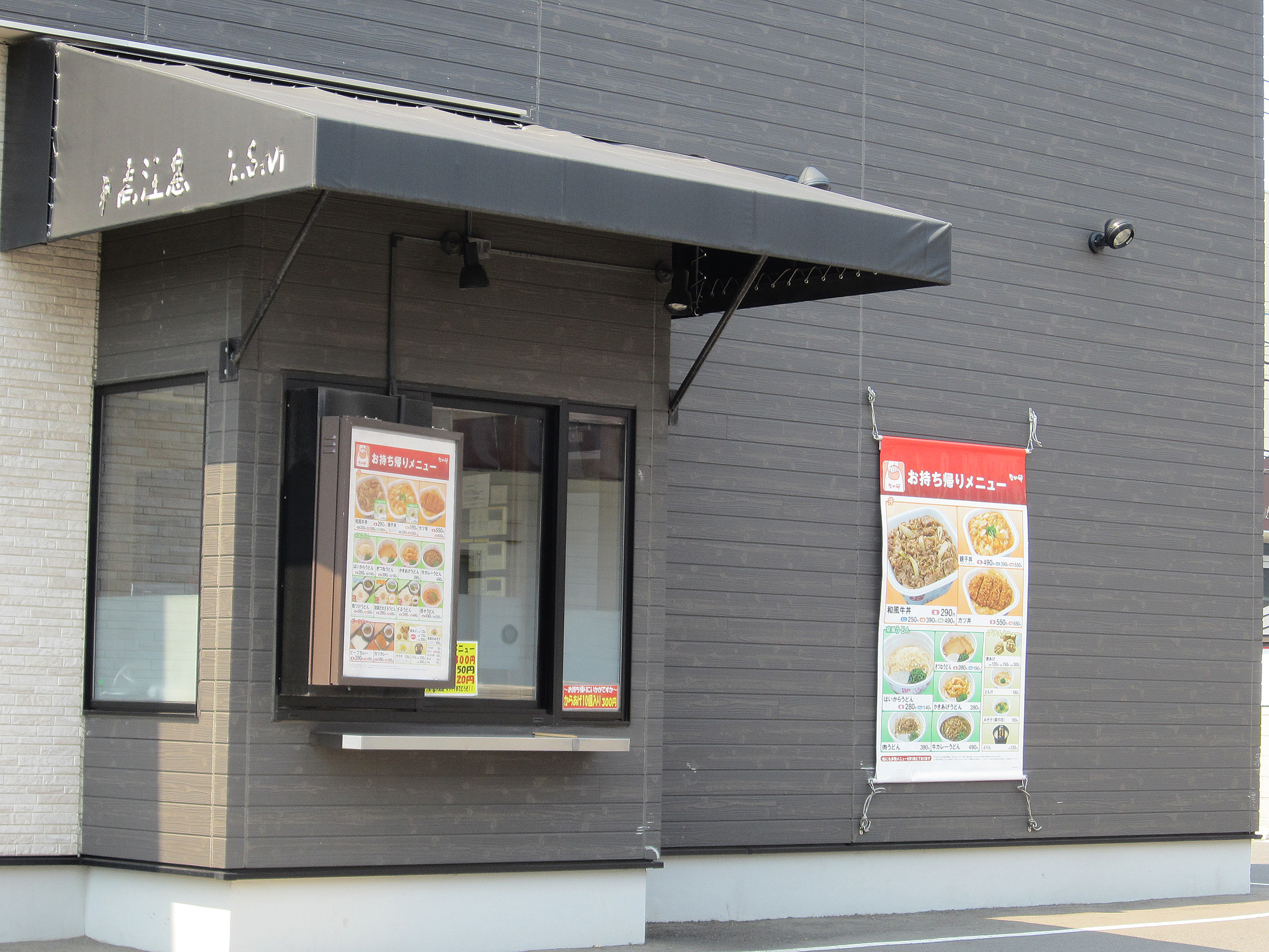 A fast food drive-through lane and menu board, where AI drive-thru ordering systems now take customer orders