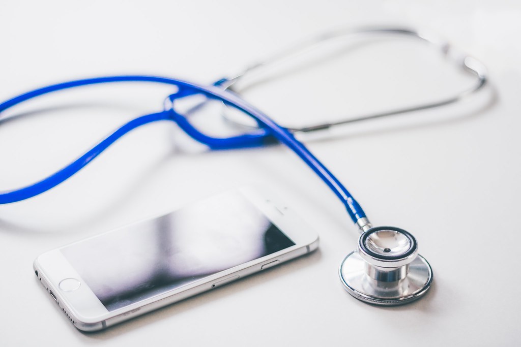 Smartphone and stethoscope on a desk, illustrating AI-generated doctors giving health advice on TikTok