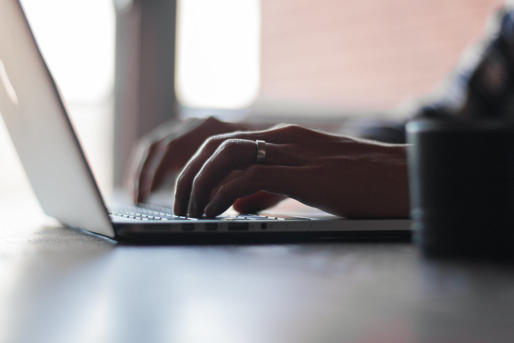 Hands typing on a laptop keyboard, illustrating writing that could be falsely accused of using AI