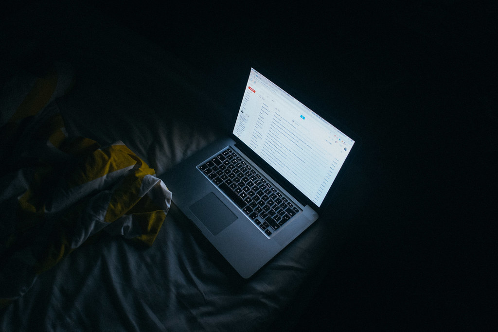 Laptop showing an email inbox at night, illustrating how hidden text in an email can fool AI summaries