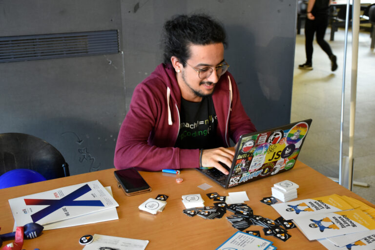 Hands typing on a sticker-covered laptop, illustrating OpenAI hacking AI GPT-5.6-Cyber and security research
